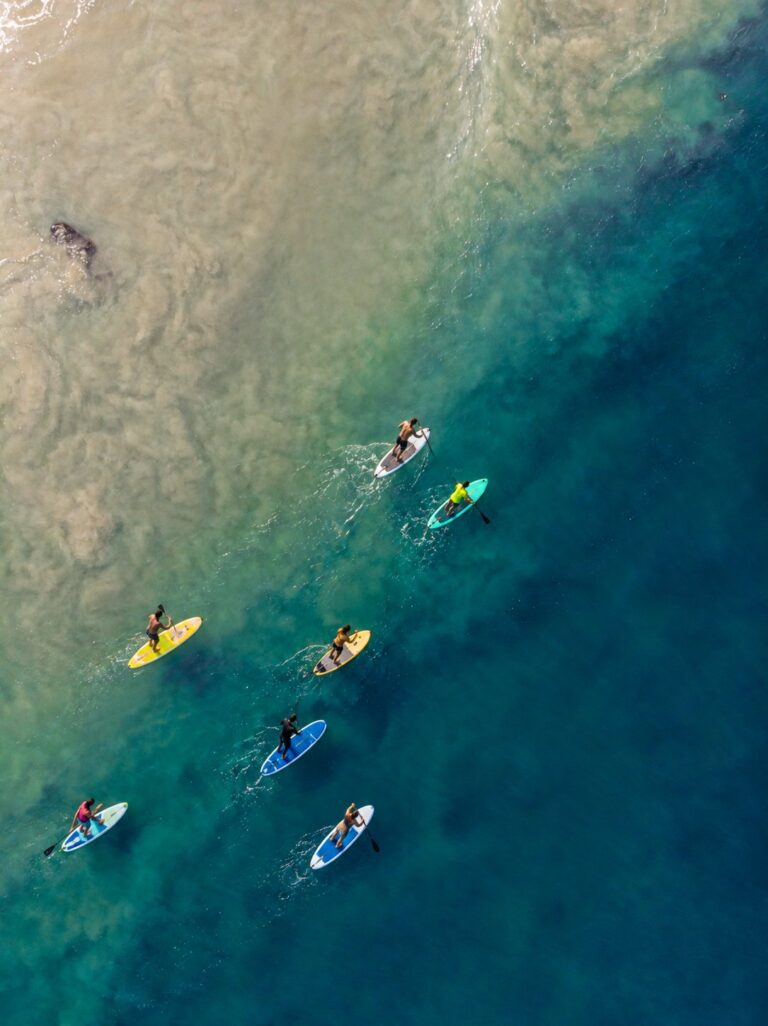 Grupo de personas practicando paddle surf sobre aguas turquesas, vistas desde el aire